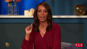 A woman in a professional burgundy dress gestures while speaking