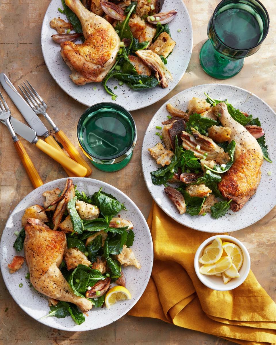 three plates of cider braised chicken and fennel panzanella with cups and silverware