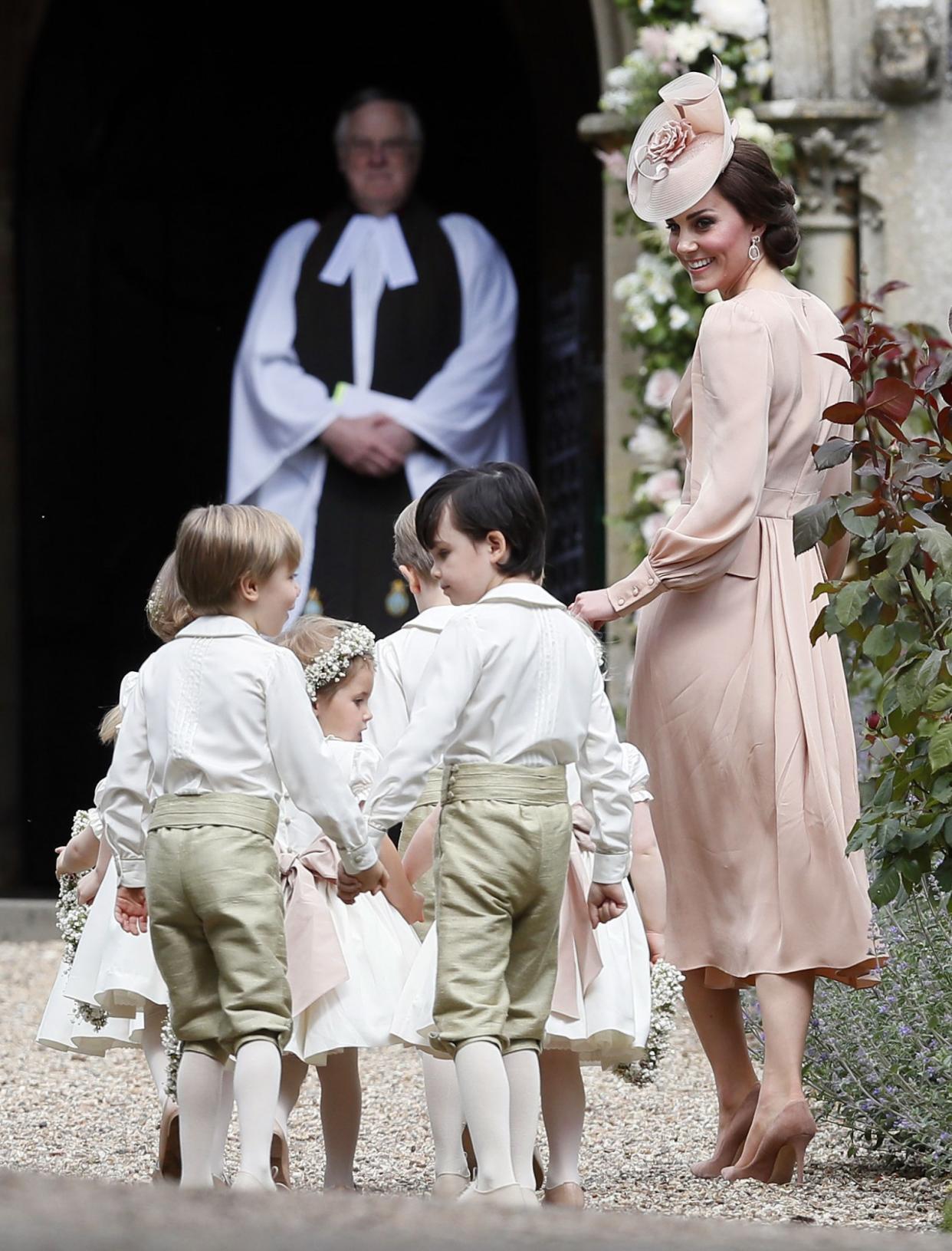 Kate made sure to not upstage her sister by wearing a dress from Alexander McQueen. The rose pink design was a midi style with a V-neck that she paired with a matching floral hat and suede heels. (Photo: PA)