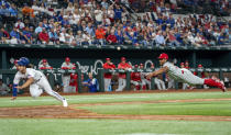 Philadelphia Phillies relief pitcher Gregory Soto, right, flips the ball toward home plate to try to put out Texas Rangers' Josh Smith, left, on an infield single by Rangers' Nathaniel Lowe during the fourth inning of an opening day baseball game, Thursday, March 30, 2023, in Arlington, Texas. (AP Photo/Jeffrey McWhorter)