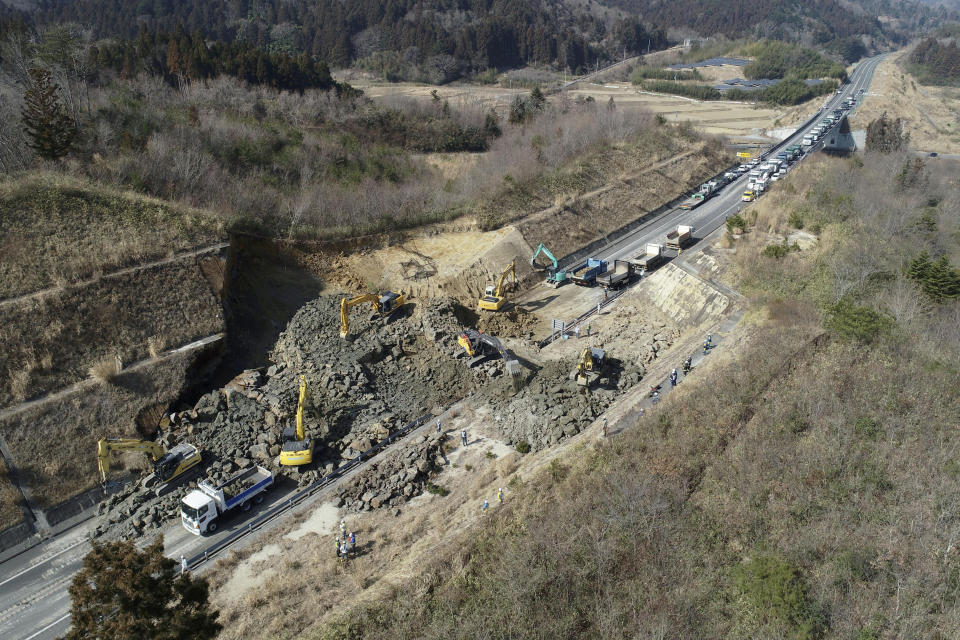 Heavy machinery work to remove a landslide blocking Joban Expressway after a strong earthquake hit Soma city, Fukushima prefecture, northeastern Japan, Sunday, Feb. 14, 2021. The strong earthquake shook the quake-prone areas of Fukushima and Miyagi prefectures late Saturday, setting off landslides and causing power blackouts for thousands of people. (Yusuke Ogata/Kyodo News via AP)