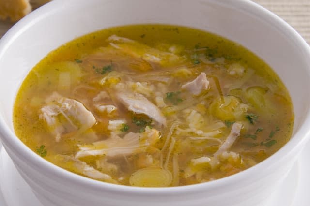 Cock-a-Leekie, traditional Scottish chicken and leek soup, served in bowl, with bread, close-up