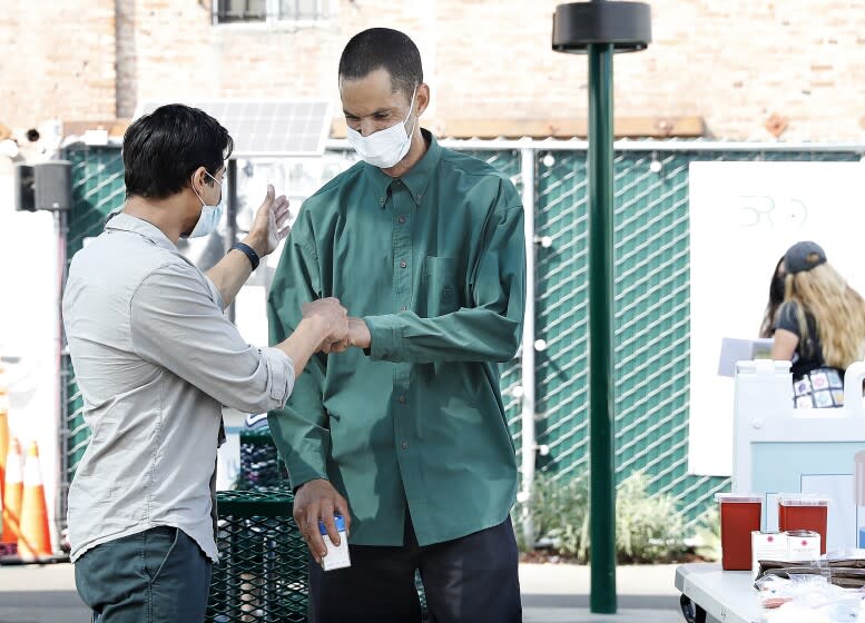 LOS ANGELES-CA-JUNE 7, 2022: Dr. Siddarth Puri, an addiction psychiatrist, left, from LAC + USC Medical Center greets Damion Corral, 45, right, a participant in "contingency management": a treatment approach that offers rewards for avoiding drug use at Skid Row Community ReFresh Spot June 7, 2022. (Christina House / Los Angeles Times)