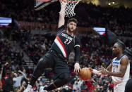Portland Trail Blazers center Jusuf Nurkic, left, hangs on the rim after dunking in front of to Minnesota Timberwolves guard Jaylen Nowell during the first half of an NBA basketball game in Portland, Ore., Tuesday, Jan. 25, 2022. (AP Photo/Craig Mitchelldyer)