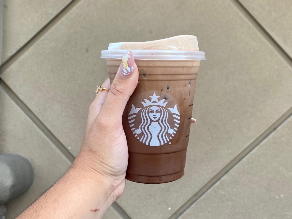 Melissa holding a Starbucks' Grande Wednesday Addams.