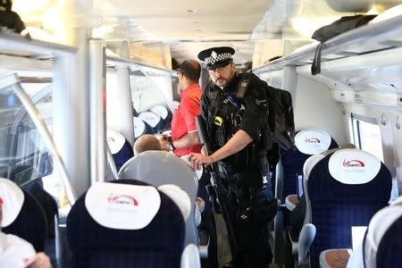 Armed police officers walk along the aisle of a train at Milton Keynes station, Britain May 25, 2017. REUTERS/Neil Hall