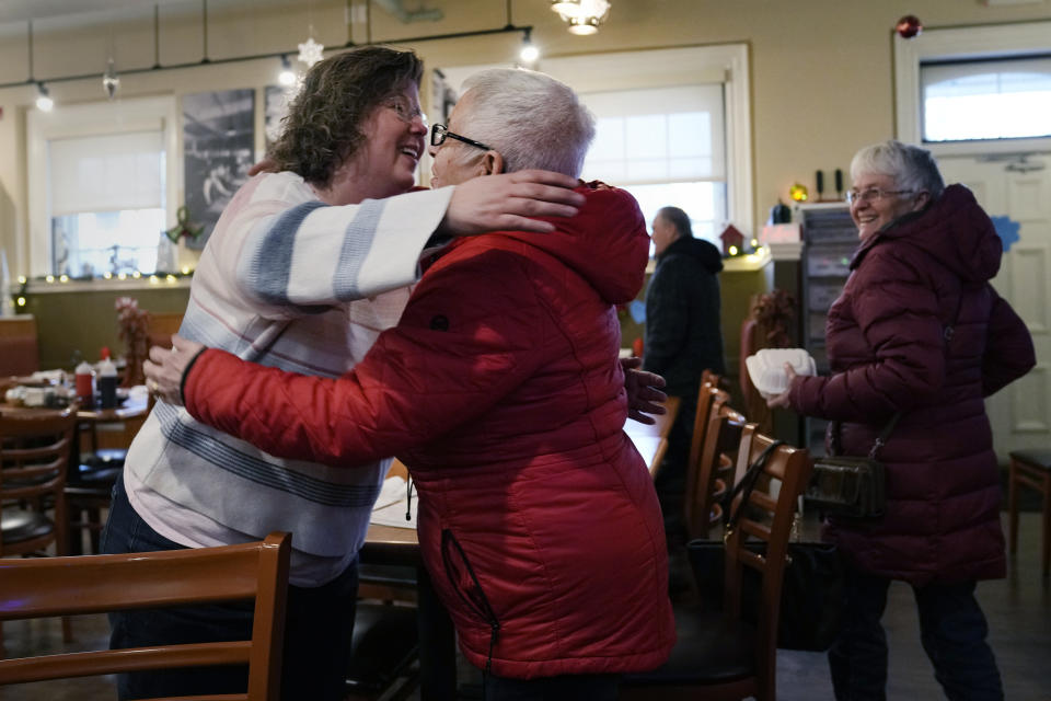 Kathy Lebel, the owner of Schemengees Bar & Grille, left, embraces lunch patron Madeline Beaupre, of Sabattus, Maine, at the Station Grill restaurant, her other business, Wednesday, Dec. 27, 2023, in Lewiston, Maine. (AP Photo/Charles Krupa)