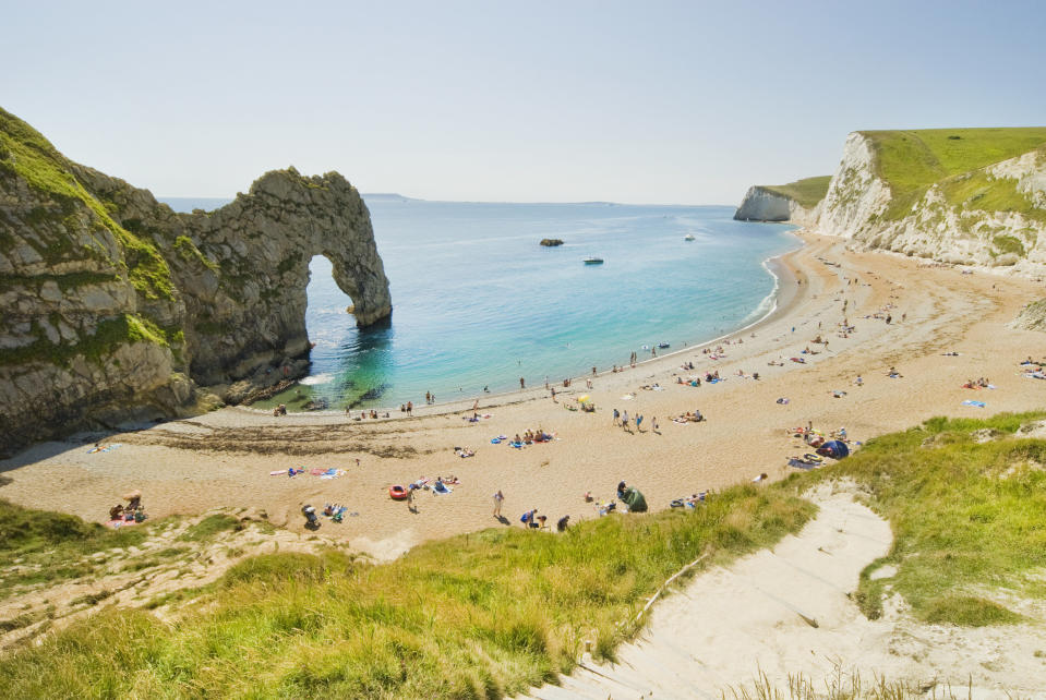 A rock formation on a coast with beachgoers