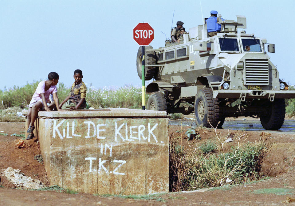 FILE - Children in Tokoza watch a military vehicle pass by on patrol in the strife-torn township East of Johannesburg, South Africa on April 10, 1994. South Africa is engrossed in debate over the legacy of apartheid's last president, F.W. de Klerk, who died last week at 85. (AP Photo/David Brauchli, File)