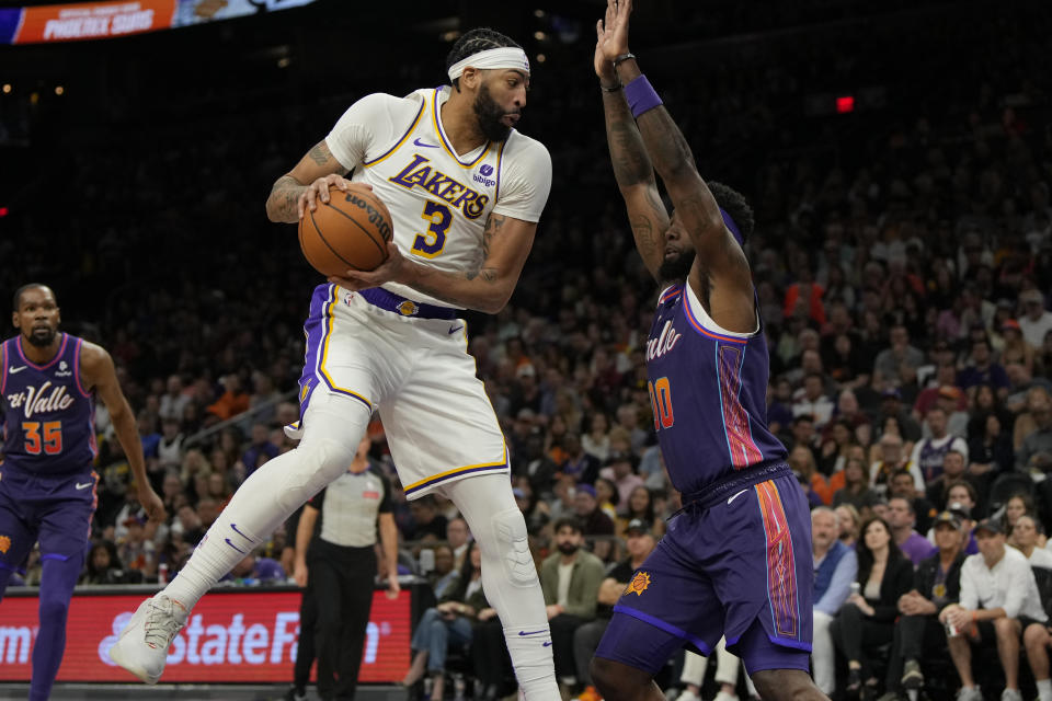 Los Angeles Lakers forward Anthony Davis (3) drives on Phoenix Suns forward Royce O'Neale during the first half of an NBA basketball game, Sunday, Feb. 25, 2024, in Phoenix. (AP Photo/Rick Scuteri)