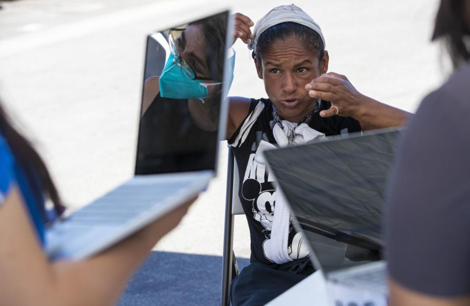 A woman speaks with nurses holding laptops