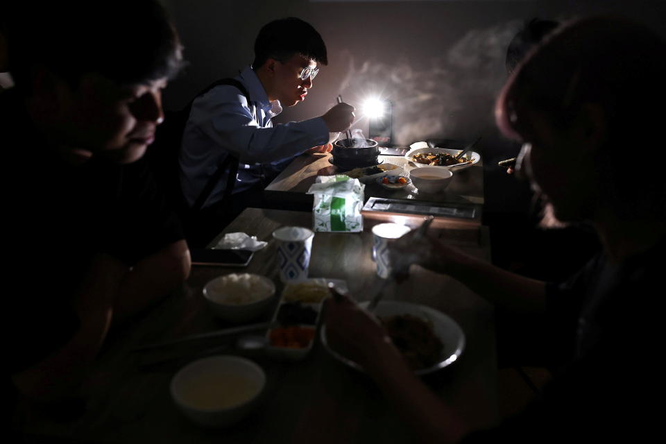 People eat using the light from their phone while experiencing a blackout due to an outage at a power plant, in Taipei, Taiwan, May 13, 2021. REUTER/Ann Wang     TPX IMAGES OF THE DAY