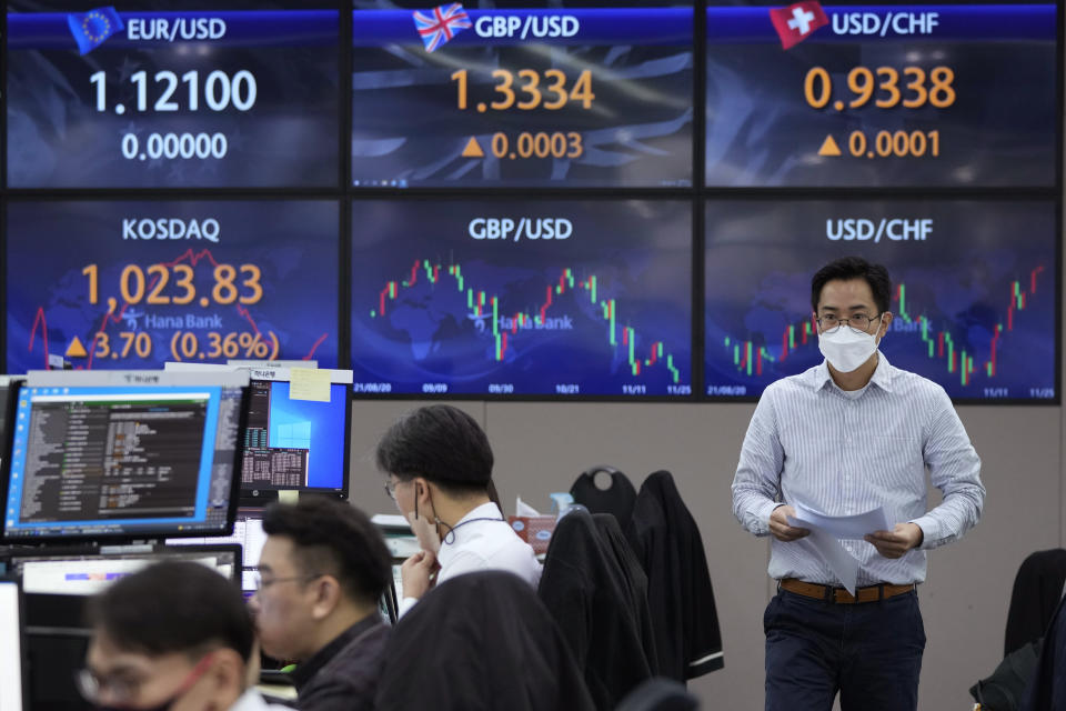 A currency trader walks by the screens showing the foreign exchange rates at the foreign exchange dealing room of the KEB Hana Bank headquarters in Seoul, South Korea, Thursday, Nov. 25, 2021. Asian stock markets fell Thursday after Federal Reserve officials indicated they were ready to raise interest rates sooner than expected if needed to cool inflation.(AP Photo/Ahn Young-joon)