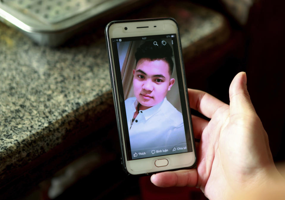 FILE - In this Oct. 28, 2019 file photo, Hoang Thi Ai, mother of Hoang Van Tiep, who is feared to be among the England truck dead, hold a phone showing a photo of Tiep in Dien Thinh village, Nghe An province, Vietnam. Ten teenagers were among the 39 Vietnamese found dead in a truck container in southeast England last month, local police said Friday, Nov. 8 while relaying for the first time details of those who died. Two of the dead were only 15, while the oldest was 44. Some 20 of the victims came from one province — Nghe An in north central Vietnam, around 200 kilometers (120 miles) south of Hanoi. Hoang Van Tiep was among the dead. (AP Photo/Hau Dinh)