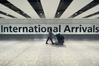 A passenger walks through International Arrivals, at London's Heathrow Airport, Friday, Nov. 26, 2021. The U.K. announced that it was banning flights from South Africa and five other southern African countries effective at noon on Friday, and that anyone who had recently arrived from those countries would be asked to take a coronavirus test. (AP Photo/Alberto Pezzali)