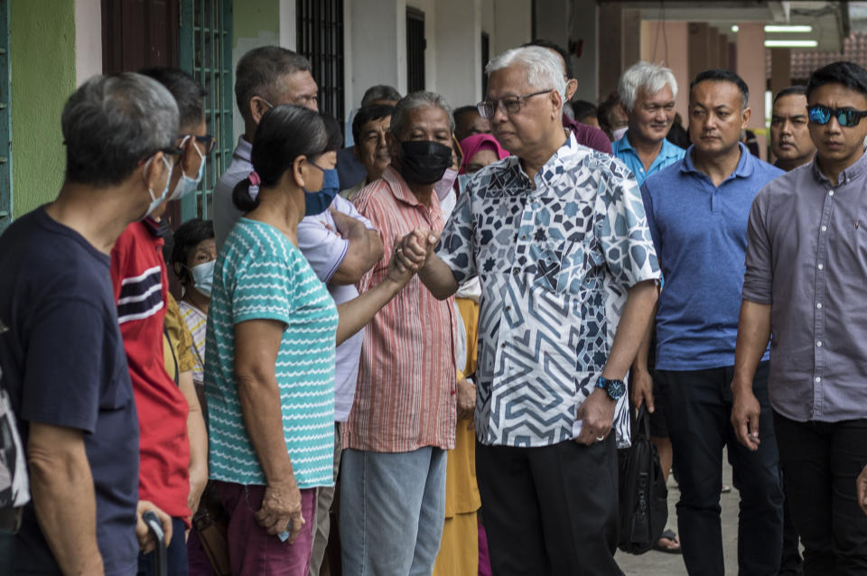 Malaysian caretaker Prime Minister Ismail Sabri Yaakob, center, chats with other voters at a polling station during the general election in Bera, Pahang, Malaysia, Saturday, Nov. 19, 2022. Malaysians began casting ballots Saturday in a tightly contested national election that will determine whether the country's longest-ruling coalition can make a comeback after its electoral defeat four years ago.(AP Photo/Ahmad Yusni)