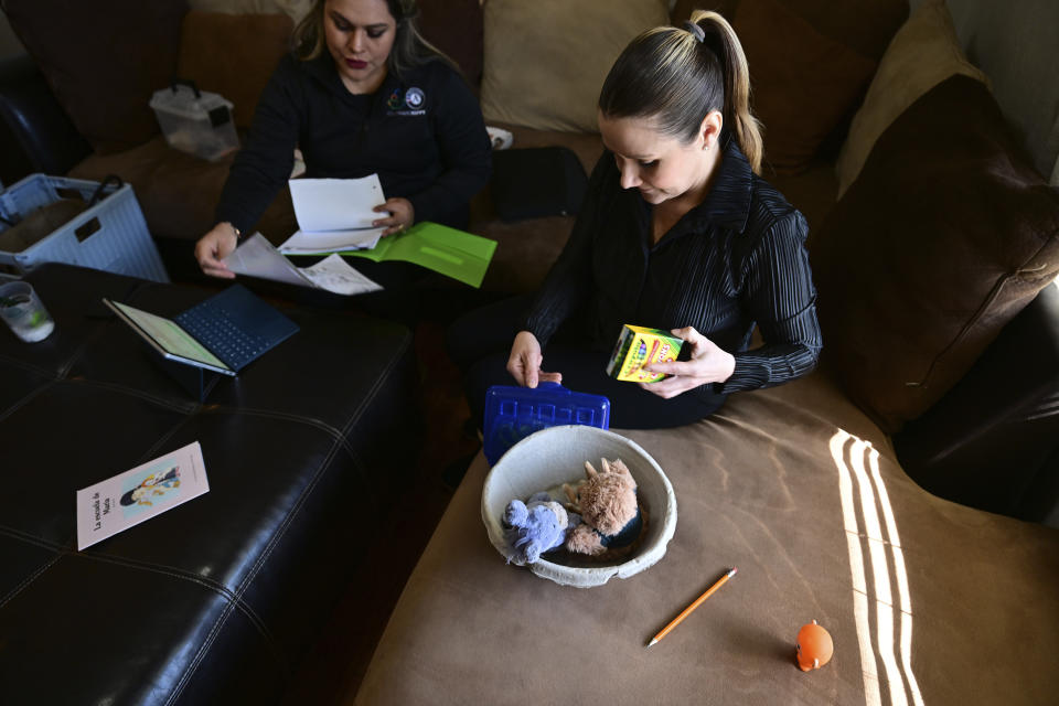 Isabel Valencia gathers props and supplies for a Home Visit HIPPY (Home Instruction for Parents of Preschool Youngsters) training session with instructor Mayra Ocampo in Valencia's home in Pueblo, Colo., Wednesday, Feb. 28, 2024. Home visit programs have provided a lifeline for families, especially those for whom access to qualify early education is scarce or out of reach financially. The programs, which are set to expand with new federal support, are proven to help prepare children for school but have reached relatively few families. (AP Photo/Eric Lars Bakke)