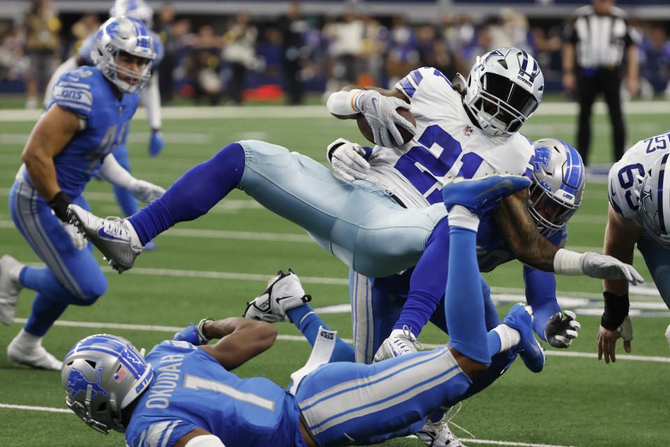 Dallas Cowboys running back Ezekiel Elliott (21) is upended by Detroit Lions cornerback Jeff Okudah (1) and linebacker Julian Okwara during the second half of an NFL football game, Sunday, Oct. 23, 2022, in Arlington, Texas. (AP Photo/Roger Steinman)