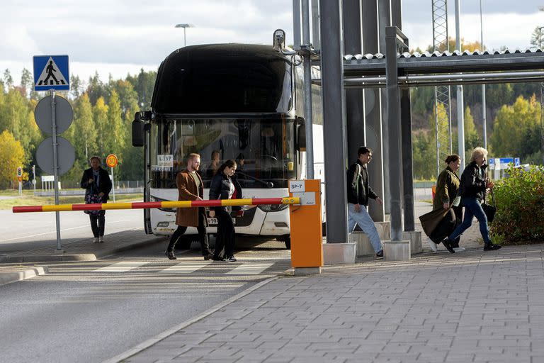 La gente baja de un ómnibus y cruza a pie la frontera entre Rusia y finalndia en el control de Nuijamaa, en Lappeenranta. (Lauri Heino/Lehtikuva via AP)