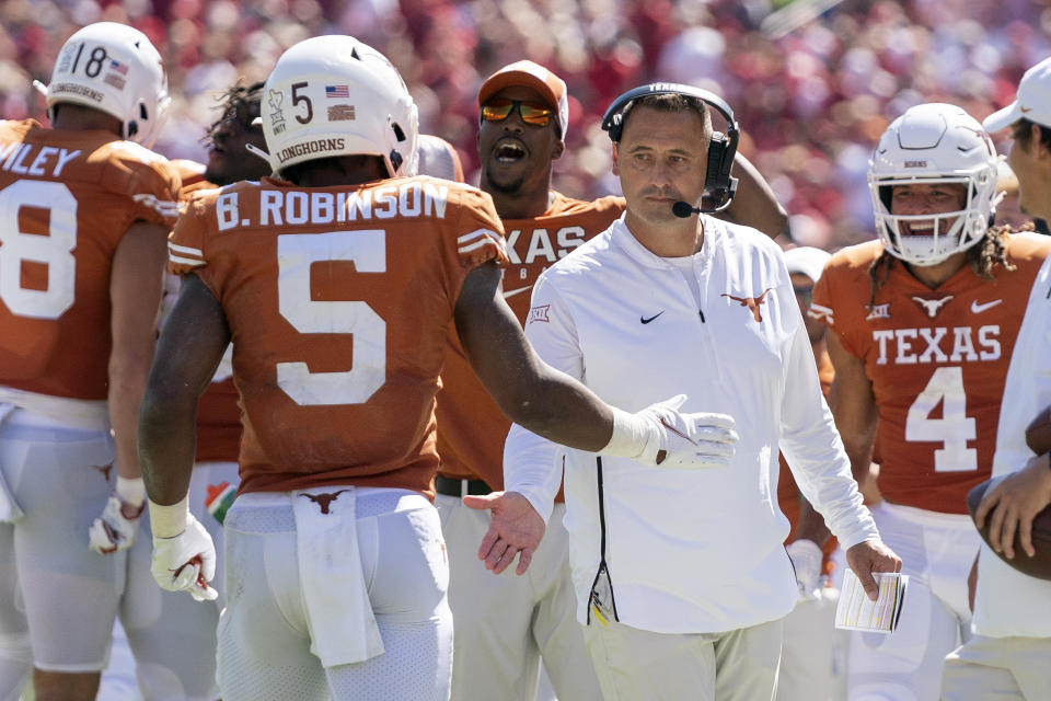 Texas head coach Steve Sarkisian congratulates running back Bijan Robinson (5) after a long run by Robinson during the first half of an NCAA college football game against Oklahoma at the Cotton Bowl, Saturday, Oct. 9, 2021, in Dallas. (AP Photo/Jeffrey McWhorter)