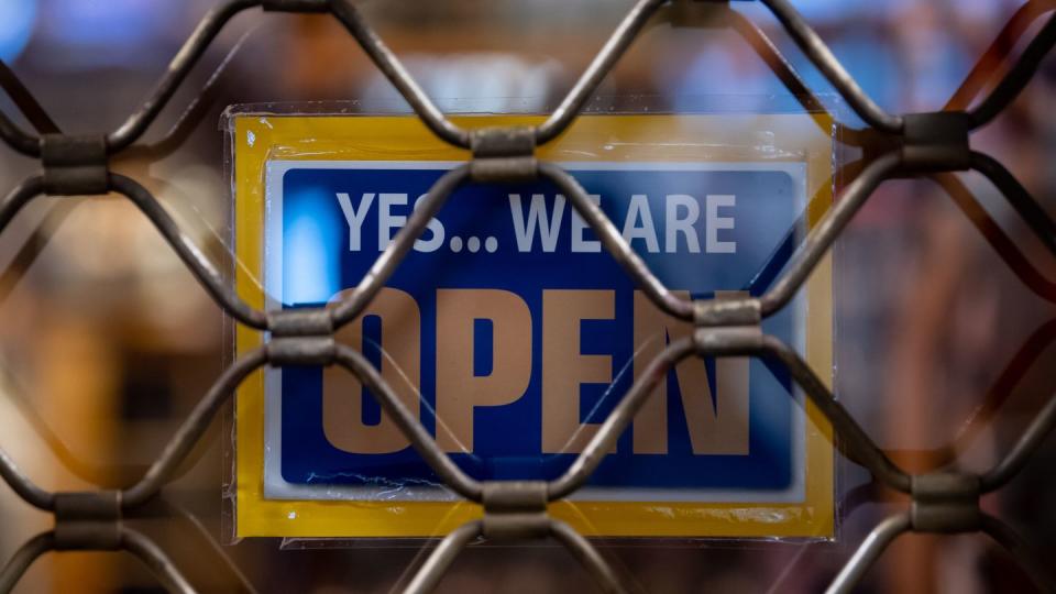 Ein Schild mit der Aufschrift «Yes...we are Open» hängt in einem Münchner Geschäft.