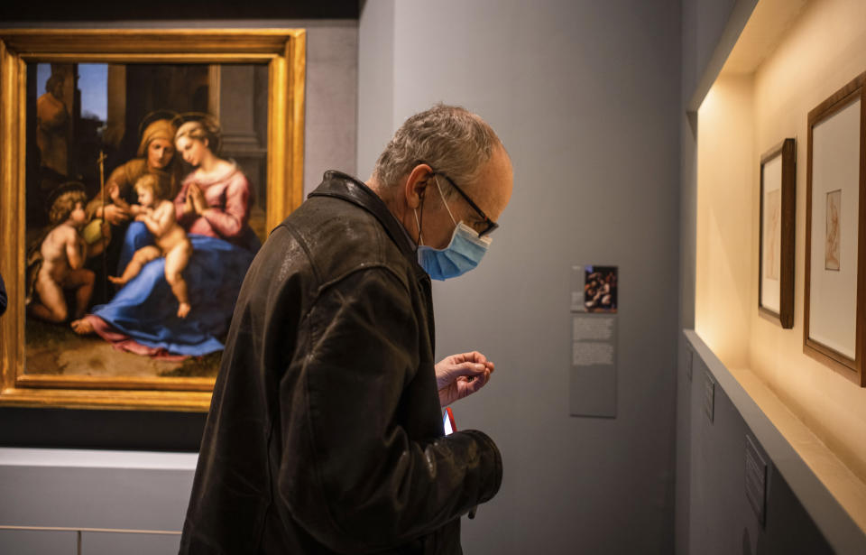 A man wearing a mask attends a press preview of Raphael's exhibition in Rome, Wednesday, March 4, 2020. The paintings, drawings and sketches in the most ambitious assemblage ever of Raphael works in an exhibition, more than even the Renaissance superstar had in his workshop at one time, are collectively insured for 4 billion euros ($.4 billion), against the likes of theft or vandalism. But no money can guarantee that Italy’s outbreak of coronavirus, the largest in Europe, won’t play havoc with the three-month run in Rome of the art world’s eagerly-awaited blockbuster. (AP Photo/Domenico Stinellis)