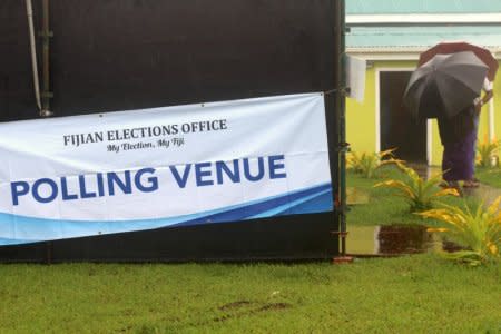 Voters walk towards a polling venue carrying umbrellas during voting for Fiji's general election near Suva, in the South Pacific nation of Fiji, November 14, 2018. REUTERS/Stringer