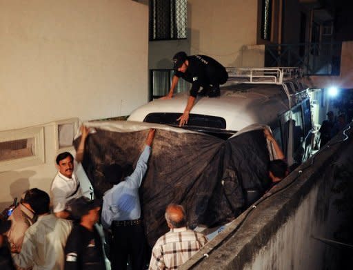 Pakistani policemen cover a minivan before boarding family members of slain Al-Qaeda chief Osama bin Laden, in Islamabad, as they leave for the airport before their departure to Saudia Arabia, on April 26