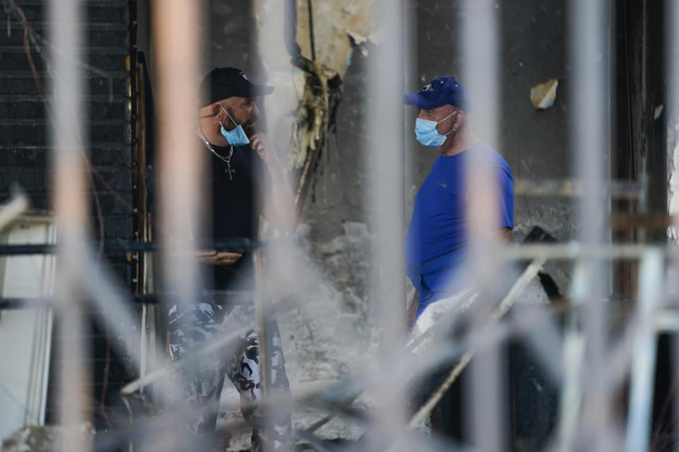 Vasken Samuelian, owner of Men's Suit Outlet, and Janik Kayajian, the manager, survey damages inside the burned store building, Monday, June 1, 2020, in Long Beach after overnight protests over the death of George Floyd died in police custody on May 25 in Minneapolis. (AP Photo/Ashley Landis)