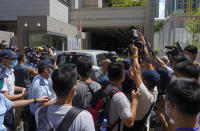 A police van is surrounded by photographers as a 23-year-old man, Tong Ying-kit, arrives at a court in Hong Kong Monday, July 6, 2020. Tong has become the first person in Hong Kong to be charged under the new national security law, for allegedly driving a motorcycle into a group of policemen while bearing a flag with the "Liberate Hong Kong, revolution of our time" slogan. (AP Photo/Vincent Yu)