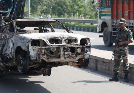 A soldier looks at a burnt out car after a day of violence in Panchkula, India August 26, 2017. REUTERS/Cathal McNaughton