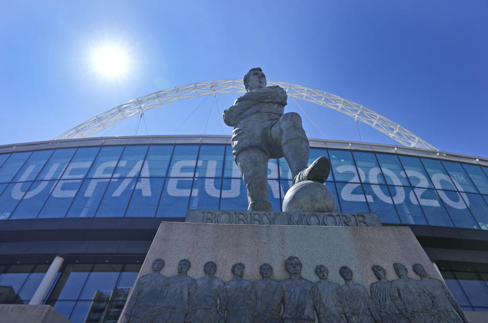 FILE - In this Wednesday, June 9, 2021 file photo, a view of the statue of England's football legend Bobby Moore stands in front of the UEFA Euro sign, at Wembley stadium entrance, ahead of the Euro 2020 soccer championship in London. The British government says more than 60,000 fans will be allowed into the semifinals and final of the European Championship at Wembley Stadium. No details have been provided yet on how fans from overseas can attend without having to quarantine after flying into London. (AP Photo/Frank Augstein, File)