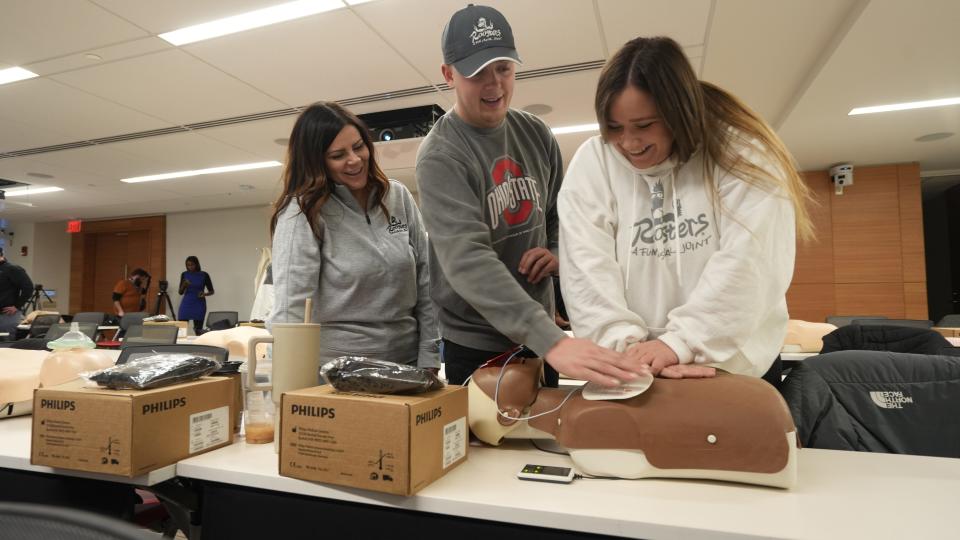 Roosters managers (from left) Jenny Pugh, Chase Kolikohn and Audrey Umpleby practice CPR on a Resusci Anne, or training doll, during an automated external defibrillator and first aid training session held at The Ohio State University Wexner Medical Center Wednesday, Jan. 3, 2024. Bob and Corrine Frick, the founders of Roosters, are buying an AED for each of their 15 corporate restaurants and staff members and managers were trained in their use at the medical center. Umpleby, Pugh and Kolikohn manage the Olentangy Road location of the popular restaurant chain.