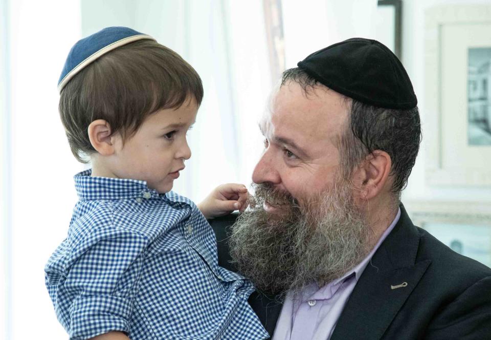 Rabbi Zalman Levitin holds his son Yaisef, 3, inside the "Mitzvah for Israel" pop-up store Thursday.