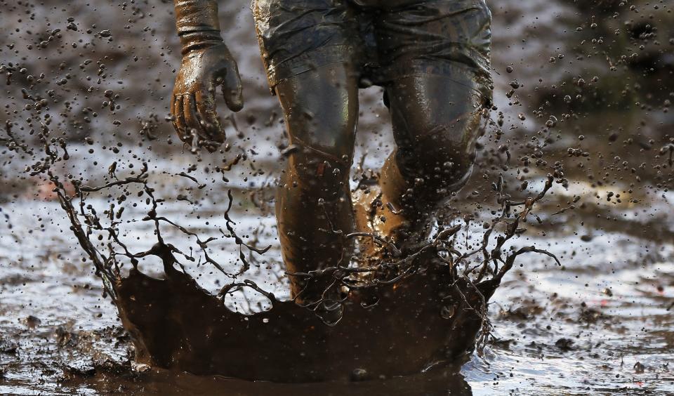 A competitor runs through mud during the Tough Guy event in Perton, central England