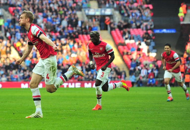 Arsenal's Per Mertesacker (L) celebrates after scoring an equalising goal to make 1-1 during their English FA Cup semi-final match against Wigan, at Wembley Stadium in London, on April 12, 2014