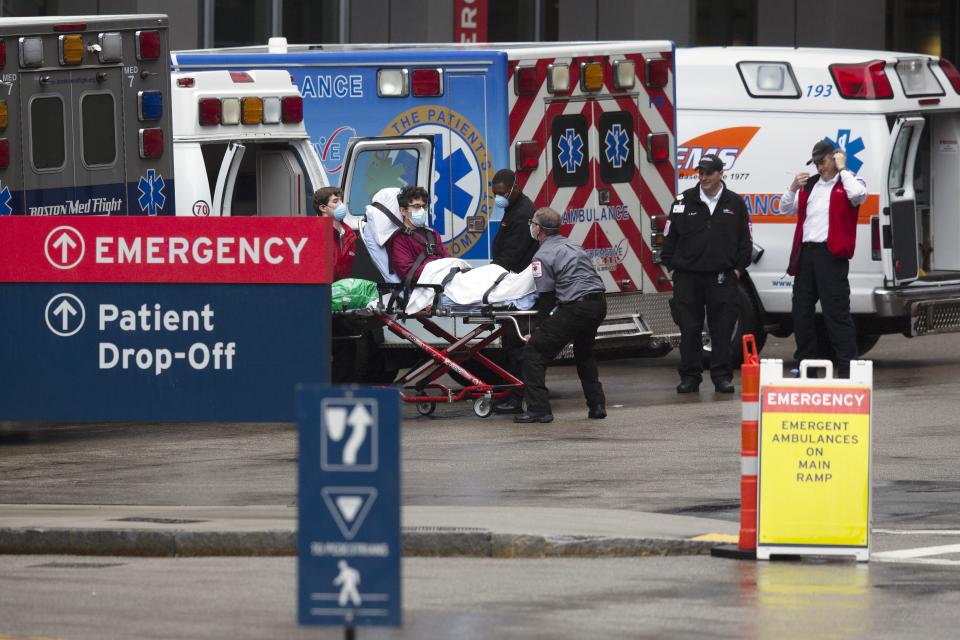 An ambulance crew transports a patient at the Massachusetts General Hospital emergency entrance, Friday, April 3, 2020, in Boston. The new coronavirus causes mild or moderate symptoms for most people, but for some, especially older adults and people with existing health problems, it can cause more severe illness or death. (AP Photo/Michael Dwyer)