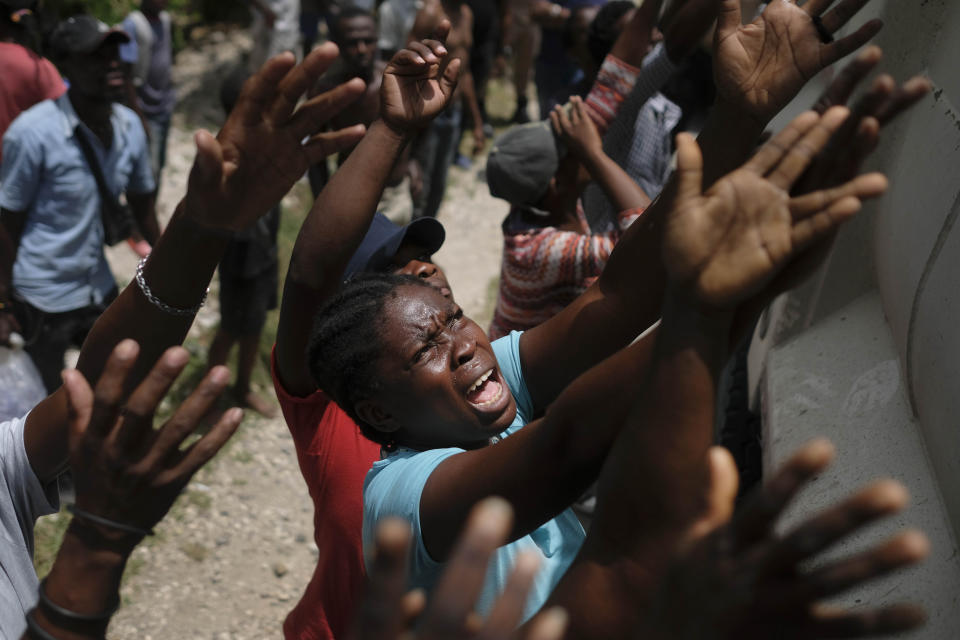 In this Aug. 22, 2021 file photo, earthquake victims reach for water being handed out during a food distribution in the Picot neighborhood in Les Cayes, Haiti, eight days after a 7.2 magnitude earthquake hit the area. (Matias Delacroix/ AP File)