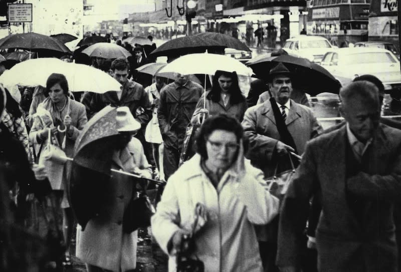 Office workers leave for home in the pouring rain in 1970.