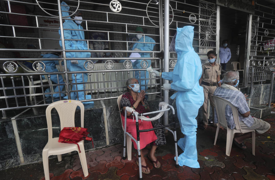 A health worker screens an elderly woman for COVID_19 symptoms at a temple in Mumbai, India, Saturday, July 18, 2020. India crossed 1 million coronavirus cases on Friday, third only to the United States and Brazil, prompting concerns about its readiness to confront an inevitable surge that could overwhelm hospitals and test the country's feeble health care system. (AP Photo/Rafiq Maqbool)