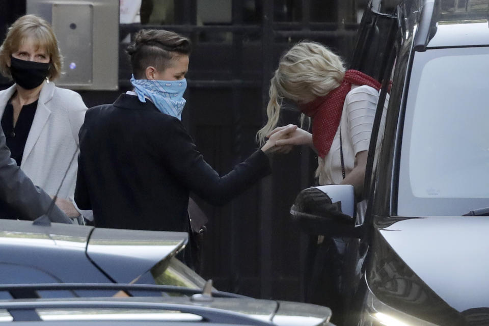 American actress Amber Heard, right, gets out of a vehicle and holds the hand of her girlfriend Bianca Butti as they arrive at the High Court in London, Monday, July 20, 2020. Amber Heard started Monday to give evidence at the High Court in London as part of Johnny Depp’s libel case against The Sun over allegations of domestic violence during the couple's relationship. (AP Photo/Matt Dunham)