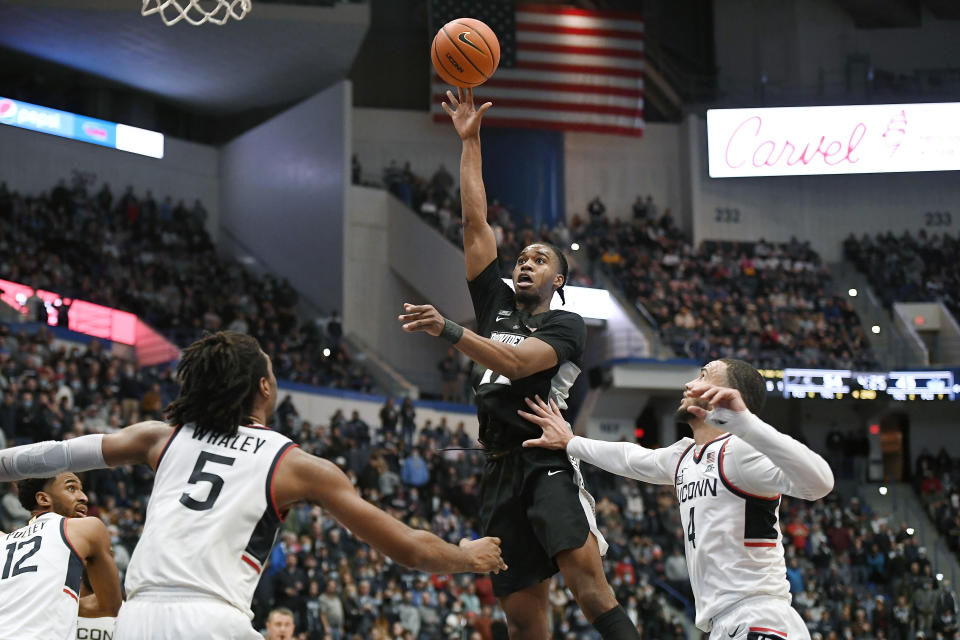 Providence's A.J. Reeves, center, shoots as Connecticut's Isaiah Whaley, left, and Connecticut's Tyrese Martin, right, defend, in the second half of an NCAA college basketball game, Saturday, Dec. 18, 2021, in Hartford, Conn. (AP Photo/Jessica Hill)