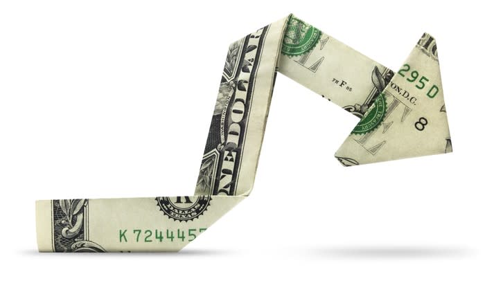 A dollar bill folded into a charting arrow pointing downward, origami-style.