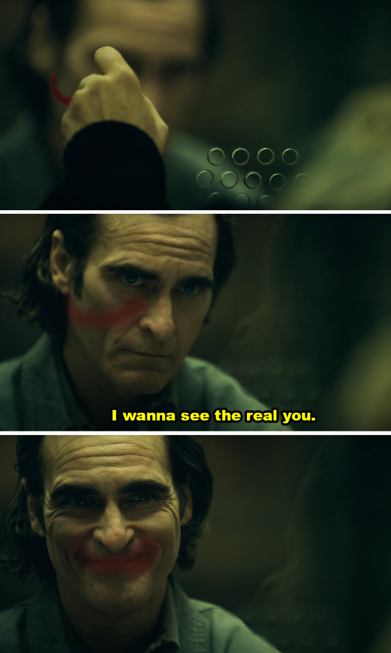 Joaquin Phoenix as Arthur Fleck looking into a mirror, applying clown makeup, captioned "I wanna see the real you."