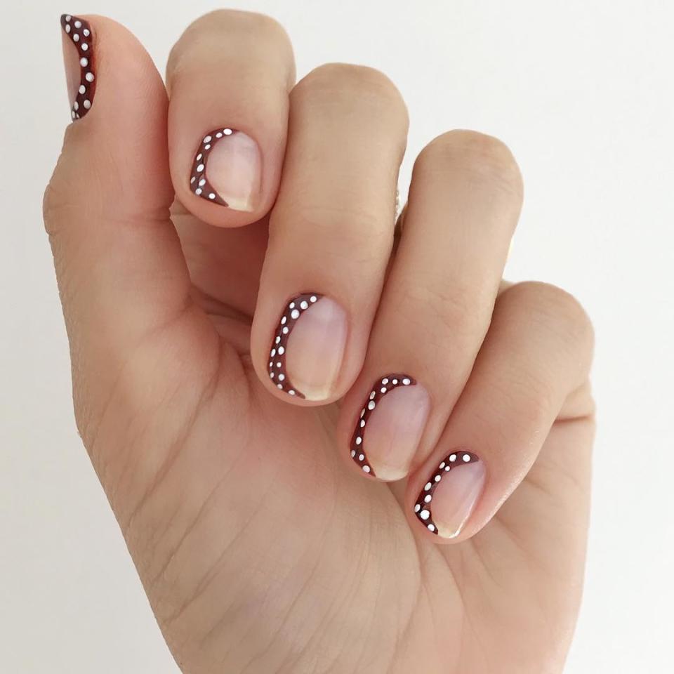 Classic polka-dots get a unique negative-space twist in this <a href="https://www.instagram.com/p/BnrXT7LBQ1C/" rel="nofollow noopener" target="_blank" data-ylk="slk:manicure by Betina Goldstein;elm:context_link;itc:0;sec:content-canvas" class="link ">manicure by Betina Goldstein</a>. She painted rich, chocolate-brown crescents along on side of each nail, dotting the darkness with a bright white polish.