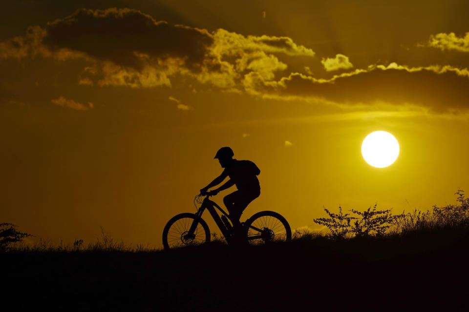 FILE - A cyclist tops a hill at sunset, Sunday, Aug. 20, 2023, in San Antonio, where temperatures continue to hit the triple digit mark. Another record-setting day of high temperatures is forecast in the Dallas/Fort Worth area Saturday, Aug. 26, 2023, before a slight cooling trend moves into the area, according to the National Weather Service as heat warnings stretch from the Gulf Coast to the Southeastern U.S. and upper Mid-South. (AP Photo/Eric Gay, File)