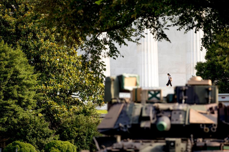 A woman walks along the columns of the Lincoln Memorial as one of two Bradley Fighting Vehicles is parked nearby for President Donald Trump's 'Salute to America' event honoring service branches on Independence Day.