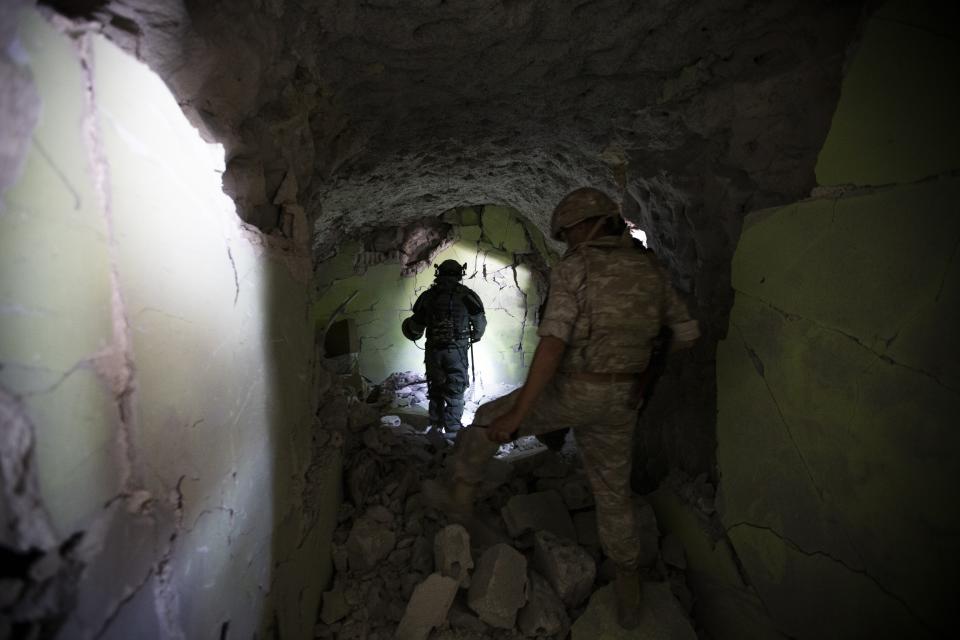 In this photo taken on Wednesday, Sept. 25, 2019, Russian military work inside caves that served as a major rebel base outside Latamna near the Syrian town of Khan Sheikhoun, Syria. The caves were dug by the rebels who controlled the area until it was captured by Syrian government troops last month. (AP Photo/Alexander Zemlianichenko)