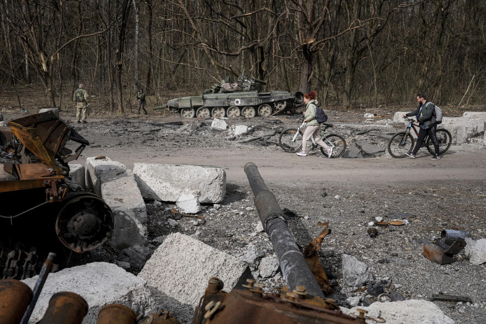 FILE - Local residents walk past destroyed Russian tanks in Chernihiv region, Ukraine, April 8, 2022. (AP Photo/Evgeniy Maloletka, File)