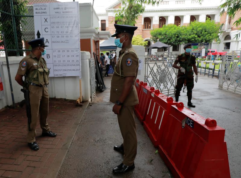 Police officers stand guard in front of a counting center on the following day of the country's parliamentary election in Colombo